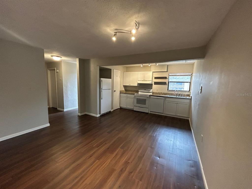 An open-concept kitchen features white cabinets, white appliances, and dark wood-look flooring — 2811 SW ARCHER ROAD UNIT C-18, GAINESVILLE, FL