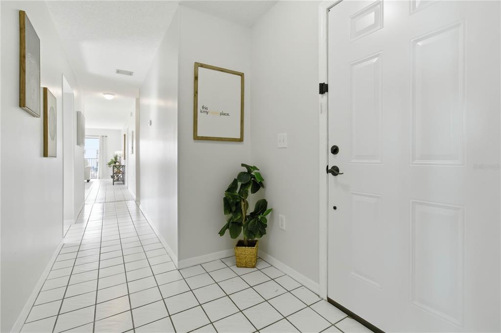 An entryway with white tile floors, a white front door, and a potted plant — 5807 N ATLANTIC AVENUE UNIT 421, CAPE CANAVERAL, FL