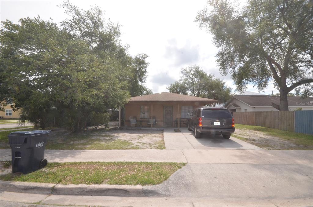 A single-story house with a concrete driveway and a large tree in the front yard — 1903 E 23RD AVENUE, TAMPA, FL