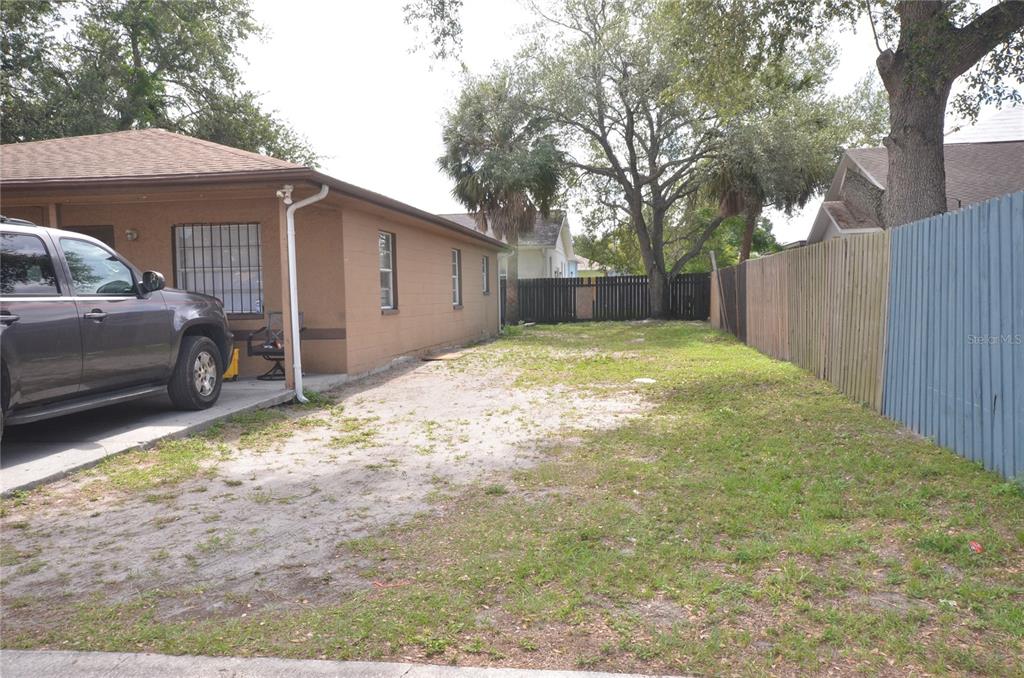 A side view of a tan house with a driveway and a wooden fence — 1903 E 23RD AVENUE, TAMPA, FL