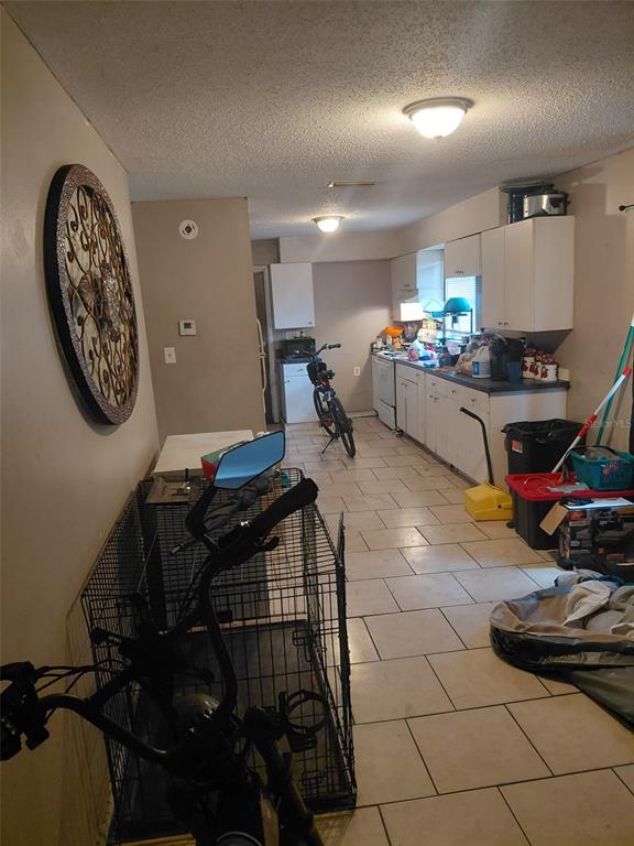 A kitchen with white cabinets, tile flooring, and a bicycle parked in the center — 1903 E 23RD AVENUE, TAMPA, FL