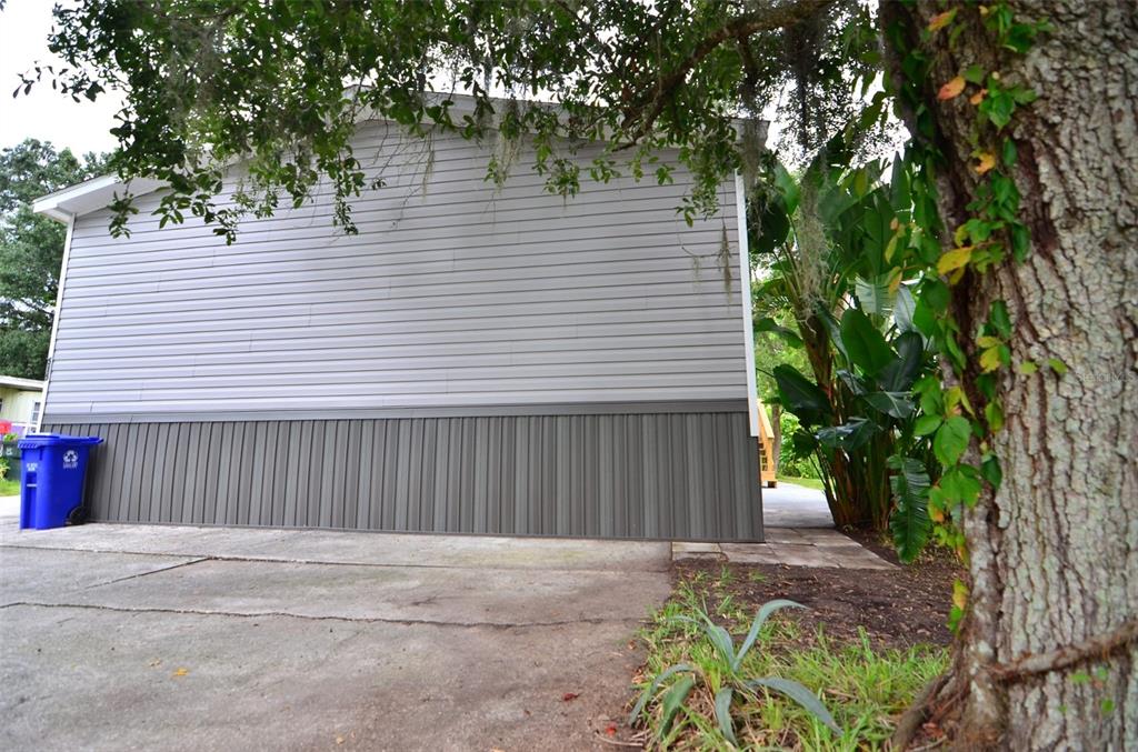 A side view of a manufactured home with light gray siding and dark vertical skirting — 515 TWIN LAKES CIRCLE, LAKELAND, FL