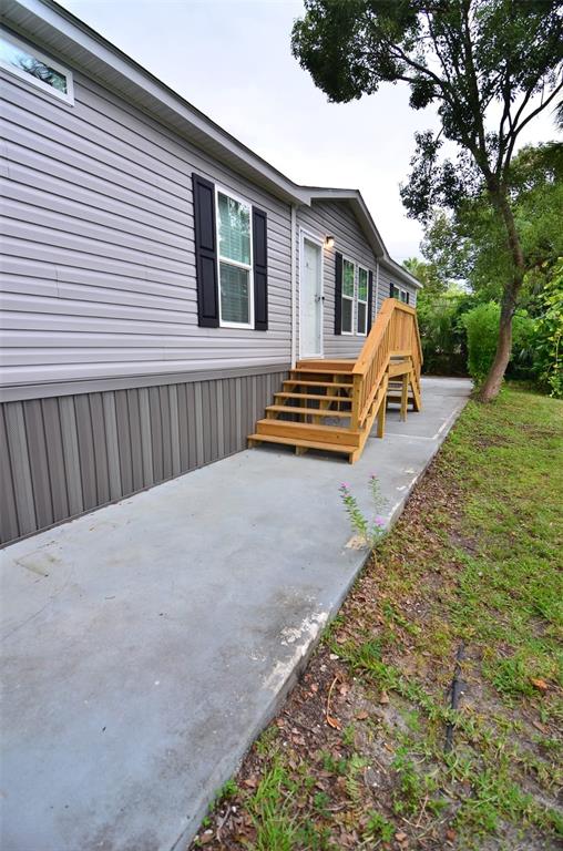 A side view of a gray mobile home with wooden stairs leading to a white door — 515 TWIN LAKES CIRCLE, LAKELAND, FL