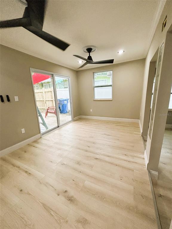 A room with light wood-look flooring, a ceiling fan, a sliding glass door, and a window — 2310 21ST STREET S, ST PETERSBURG, FL