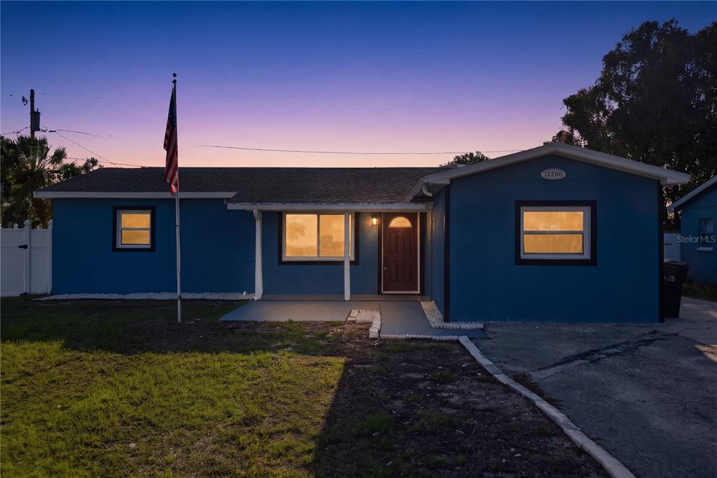 A blue single-story house with a front porch, a flag pole, and a paved driveway — 12760 118TH STREET, LARGO, FL