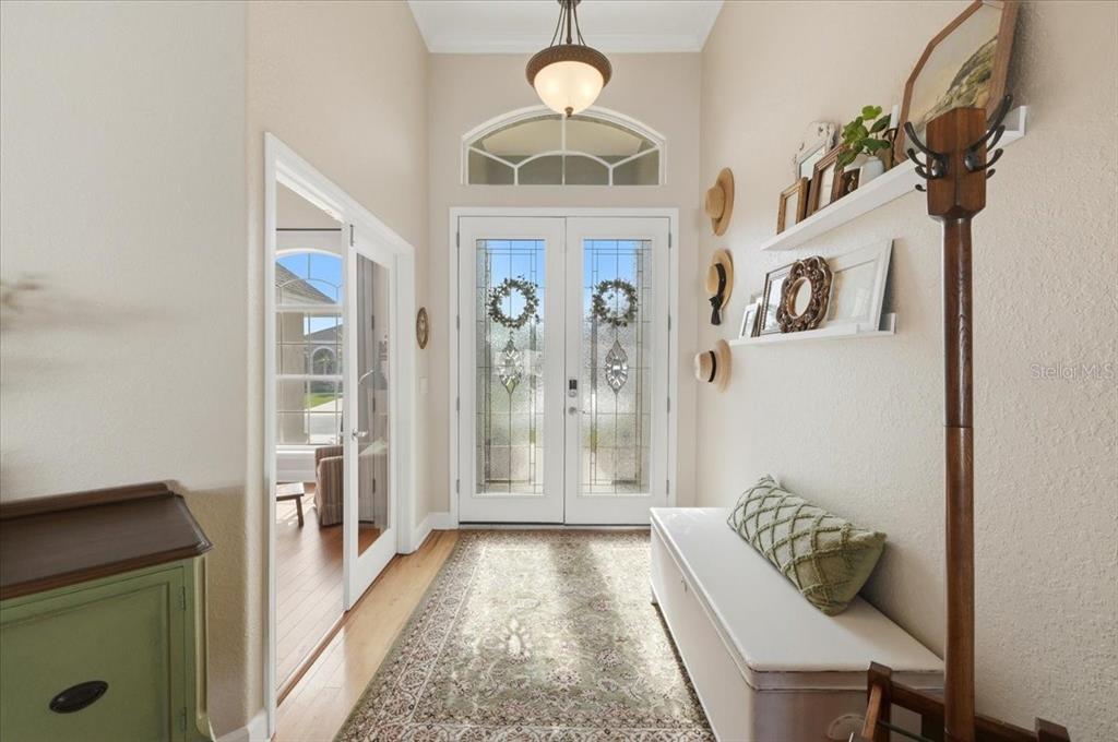 A bright entryway features double glass-paneled doors, a bench, a coat rack, and hardwood floors — 6767 HILLIS DRIVE, LAKELAND, FL