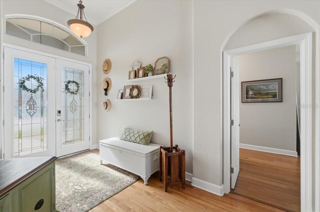 A bright entryway features a white storage bench, wall shelves, and a wooden coat rack — 6767 HILLIS DRIVE, LAKELAND, FL