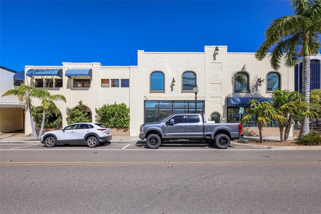 A two-story commercial building with arched windows and two parked vehicles in front — 1565 STATE STREET, SARASOTA, FL