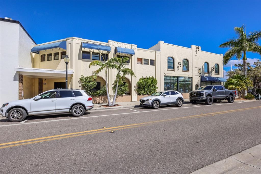 A street-level view of a light-colored commercial building with parked cars in front — 1565 STATE STREET, SARASOTA, FL