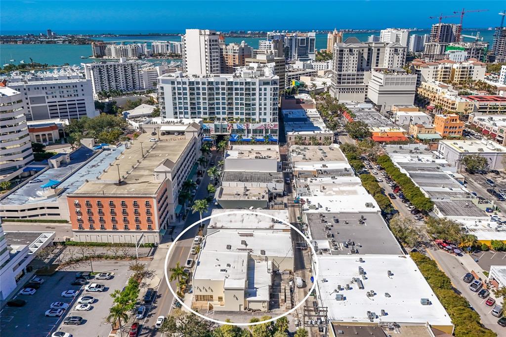 An aerial view shows a low-rise commercial building circled in a dense urban area — 1565 STATE STREET, SARASOTA, FL