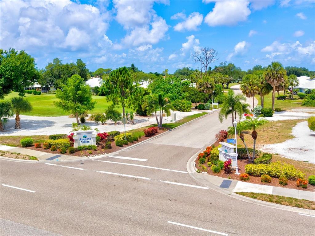 An exterior view of the Augusta Villas entrance with palm trees and landscaped signage — 316 WEXFORD TERRACE UNIT 167, VENICE, FL