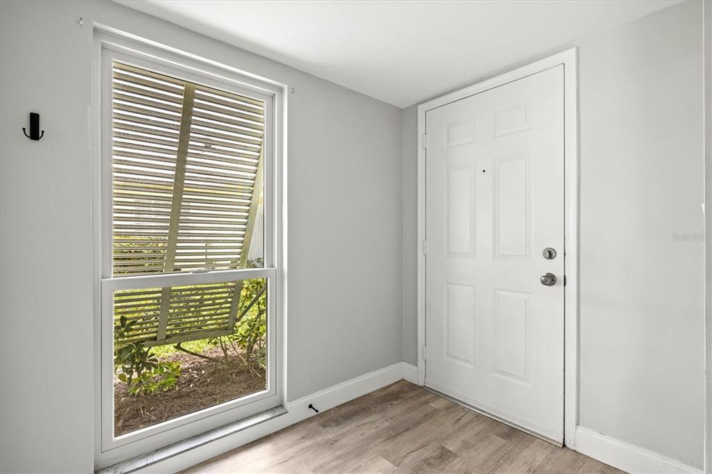 An entryway with light wood-look flooring, a white door, and a window with blinds — 316 WEXFORD TERRACE UNIT 167, VENICE, FL