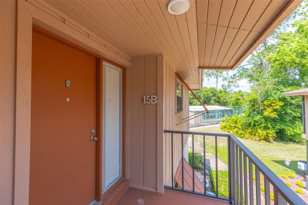 An exterior view of an apartment entrance with a brown door labeled 15B — 180 MAGNOLIA WOODS COURT UNIT 15B, DELTONA, FL