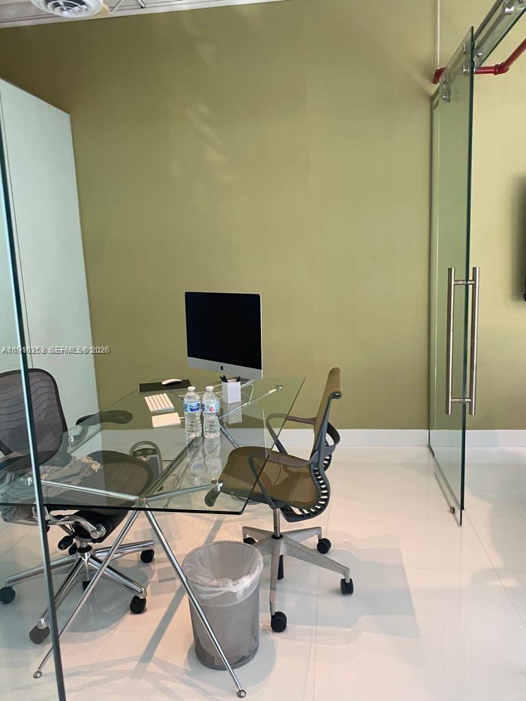 A modern office space features a glass desk, two chairs, and a computer monitor — 1110 Brickell Ave # 804, Miami FL 33131, MIAMI, FL