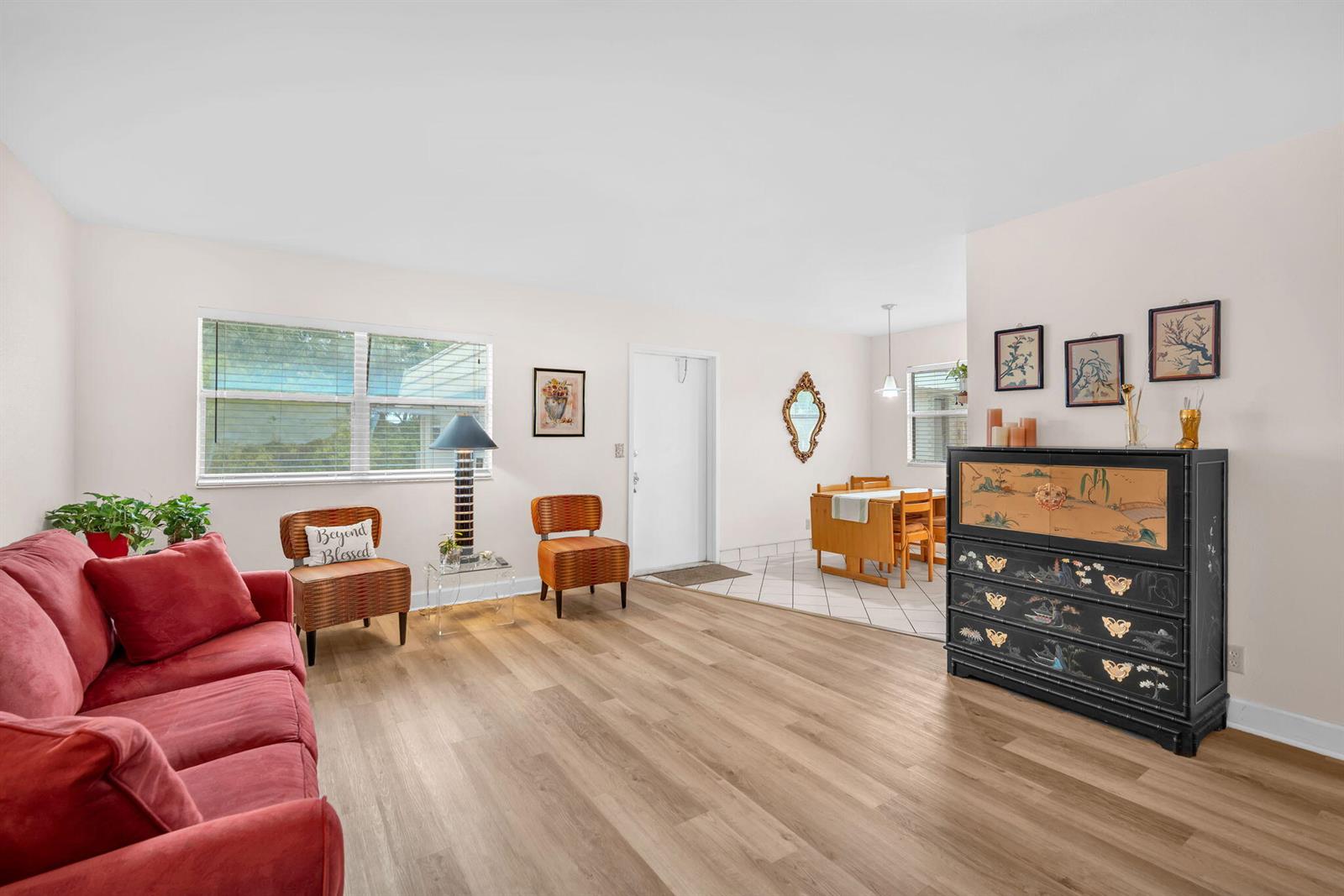 A living room with light wood flooring, a red sofa, and an adjacent dining area — 716 Saxony Place # O, Delray Beach FL 33446, DELRAY BEACH, FL