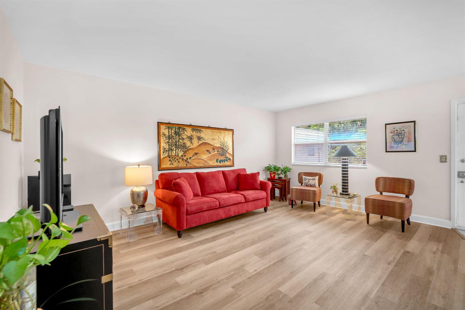 A living room features a red sofa, two patterned chairs, and light wood-look flooring — 716 Saxony Place # O, Delray Beach FL 33446, DELRAY BEACH, FL