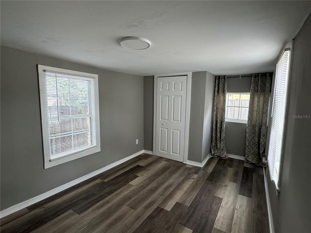 A bedroom with gray walls, wood-look flooring, two windows, and a white closet door — 602 S PROSPECT AVENUE, CLEARWATER, FL