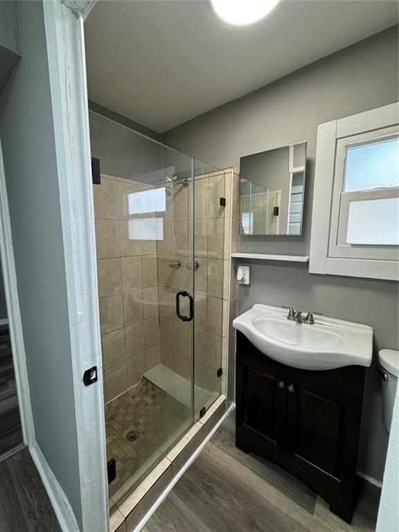 A bathroom features a glass-enclosed tiled shower, a dark wood vanity, and gray walls — 602 S PROSPECT AVENUE, CLEARWATER, FL
