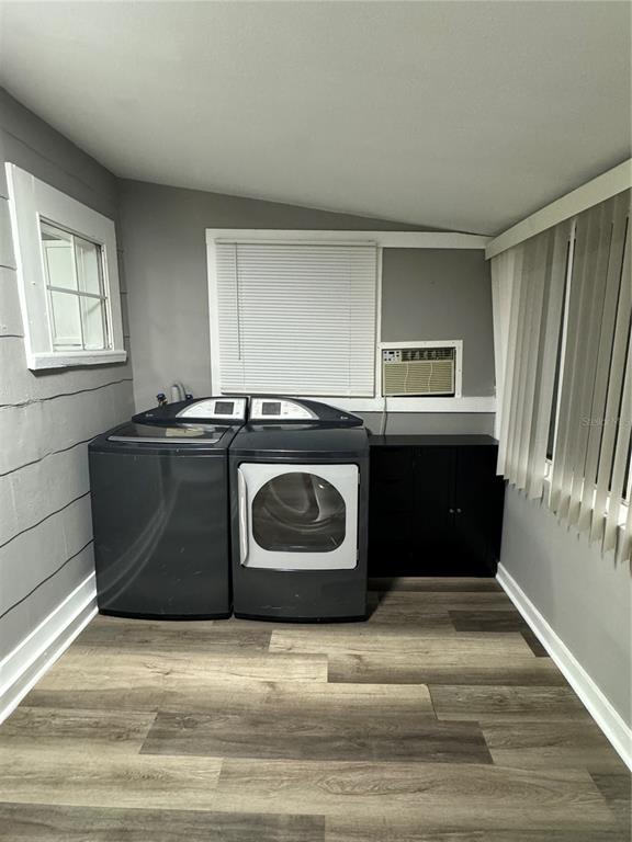 A laundry room features a washer, dryer, dark cabinet, and wood-look flooring — 602 S PROSPECT AVENUE, CLEARWATER, FL