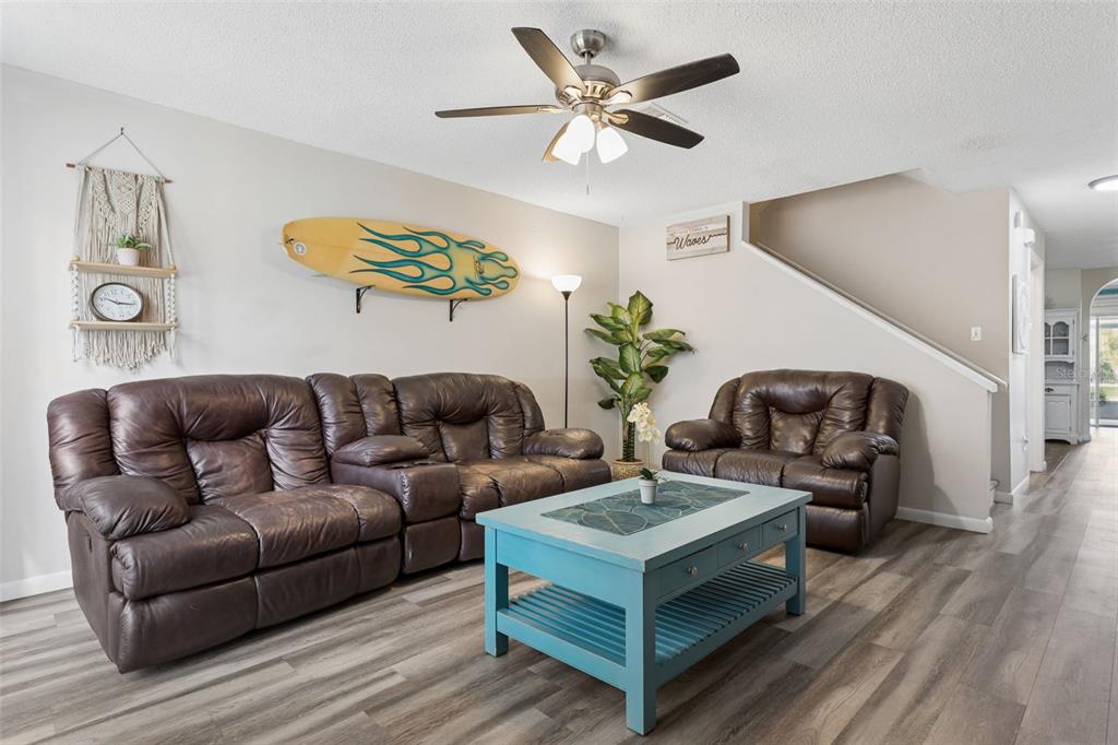 A living room features a brown leather sofa, matching armchair, and a blue coffee table — 425 KENSINGTON LAKE CIRCLE, BRANDON, FL