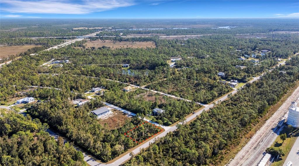 An aerial view shows a vacant, wooded residential lot outlined in red along a road — 12147 PLATANO DRIVE, PUNTA GORDA, FL