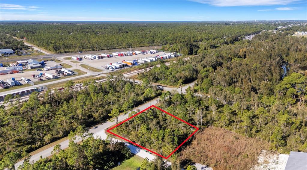 An aerial view shows a rectangular plot of land outlined in red amidst wooded surroundings — 12147 PLATANO DRIVE, PUNTA GORDA, FL