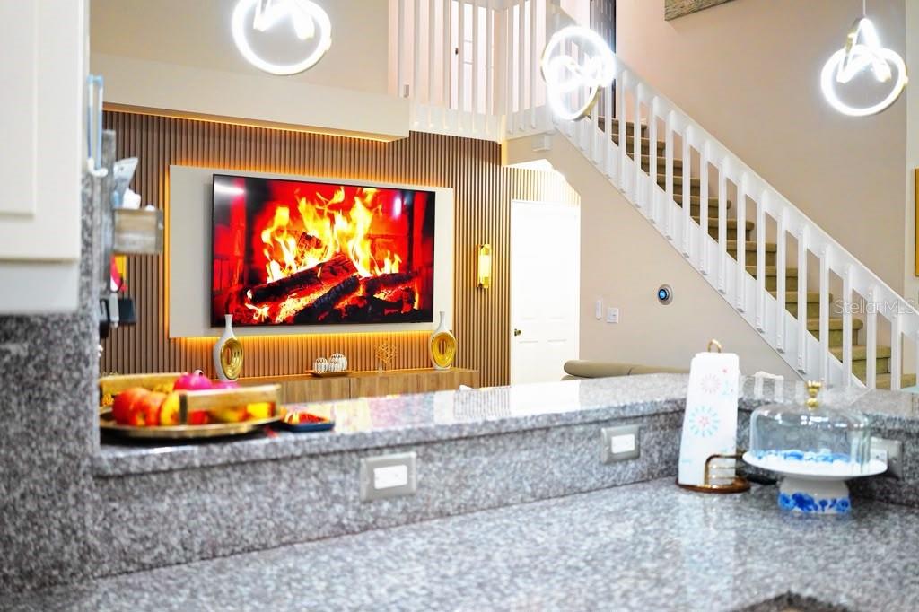 A view from a granite kitchen counter looking toward a living room with a fireplace — 2592 CHATHAM CIRCLE, KISSIMMEE, FL