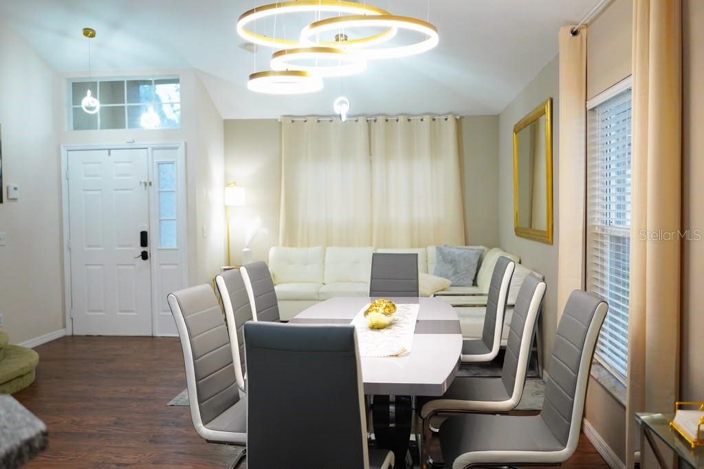 A dining area features a modern table with grey chairs beneath a tiered circular chandelier — 2592 CHATHAM CIRCLE, KISSIMMEE, FL