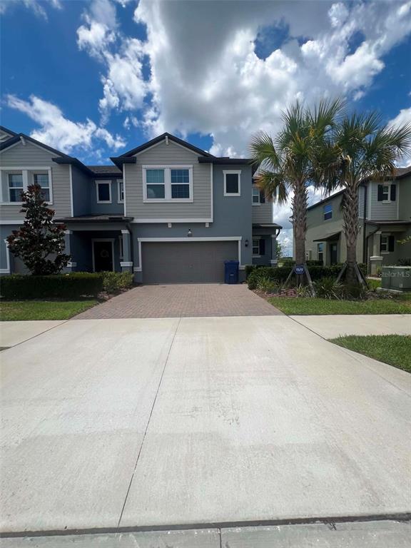 A two-story townhouse with a gray exterior, a two-car garage, and palm trees in front — 8845 GALLANTREE PLACE, LAND O LAKES, FL