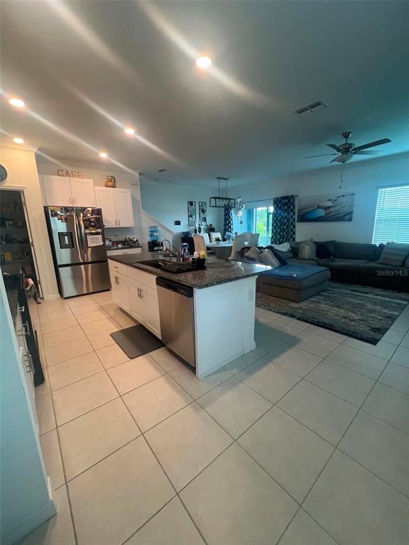 An open-concept kitchen with a granite island and stainless steel appliances overlooks a living area — 8845 GALLANTREE PLACE, LAND O LAKES, FL