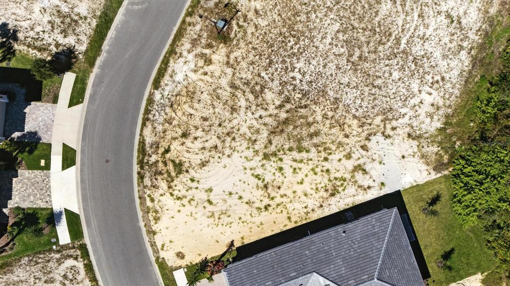 An aerial view shows a vacant, sandy residential lot situated between a curved road and a house — 6 RIO VISTA DRIVE, PALM COAST, FL