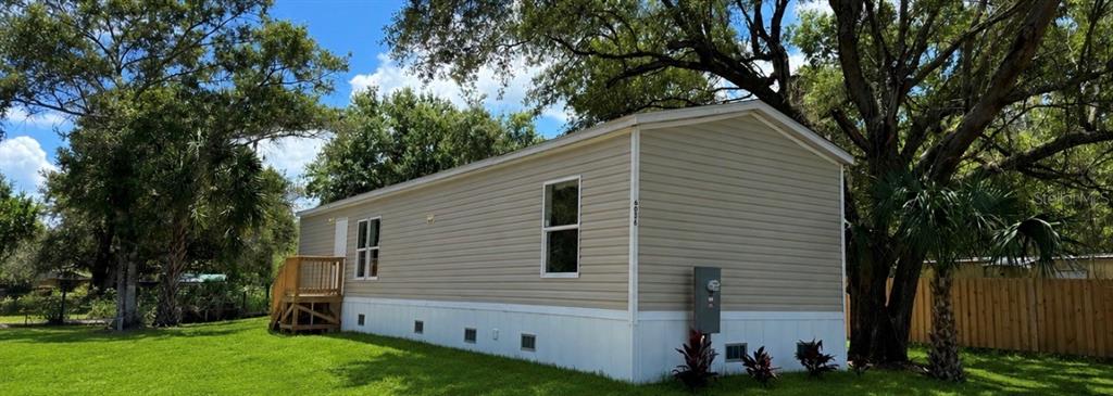 A tan mobile home with white skirting and a small wooden porch sits on grass — 6056 SW MIAMI AVENUE, ARCADIA, FL