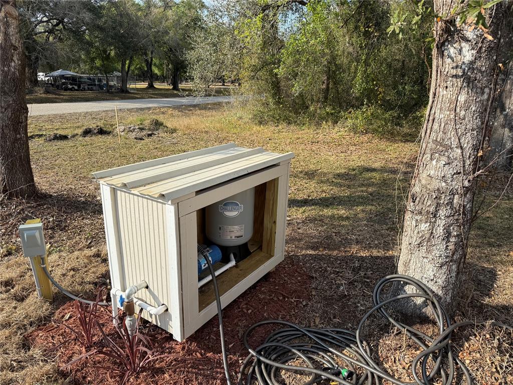 An outdoor well pump and pressure tank are housed inside a small, white wooden shed — 6056 SW MIAMI AVENUE, ARCADIA, FL