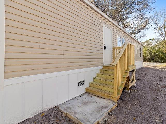 The exterior of a manufactured home features tan horizontal siding and a wooden staircase — 6056 SW MIAMI AVENUE, ARCADIA, FL