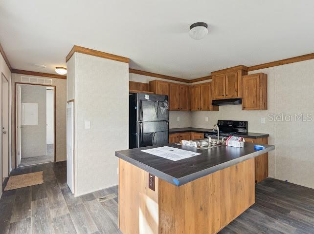 A kitchen features wood cabinets, a black refrigerator, and a dark-topped center island — 6056 SW MIAMI AVENUE, ARCADIA, FL