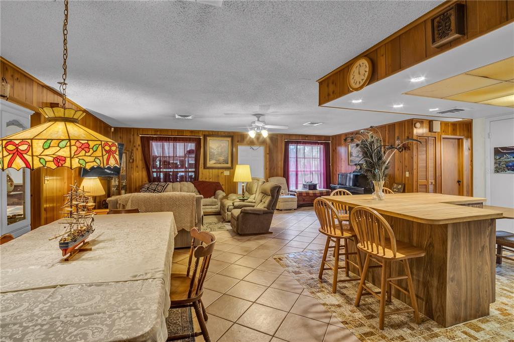 A living and dining area features wood-paneled walls, tile flooring, and a kitchen island — 14181 35TH PLACE N, LOXAHATCHEE, FL