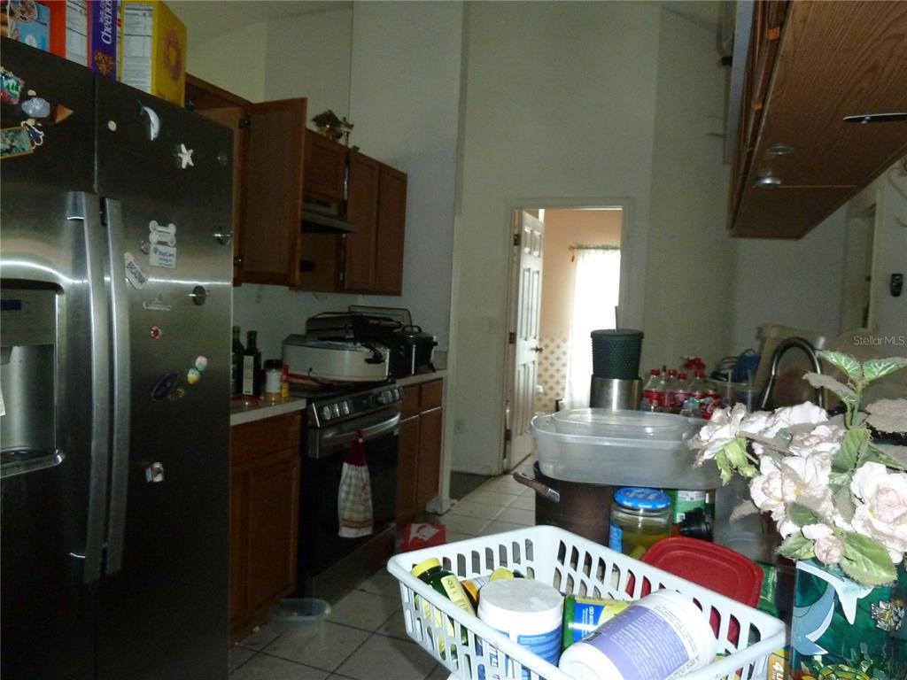 A kitchen features dark wood cabinets, stainless steel appliances, and a cluttered countertop — 5 S JUPITER AVENUE, CLEARWATER, FL