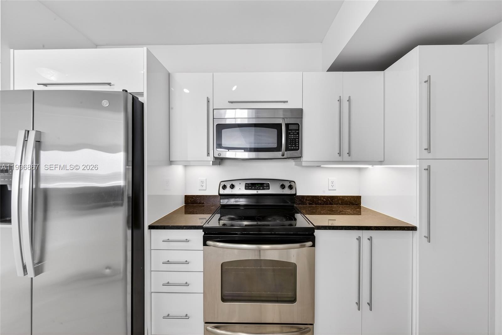 A kitchen features white cabinets, stainless steel appliances, and dark brown countertops — 7350 SW 89th St # 1703S, Miami FL 33156, MIAMI, FL