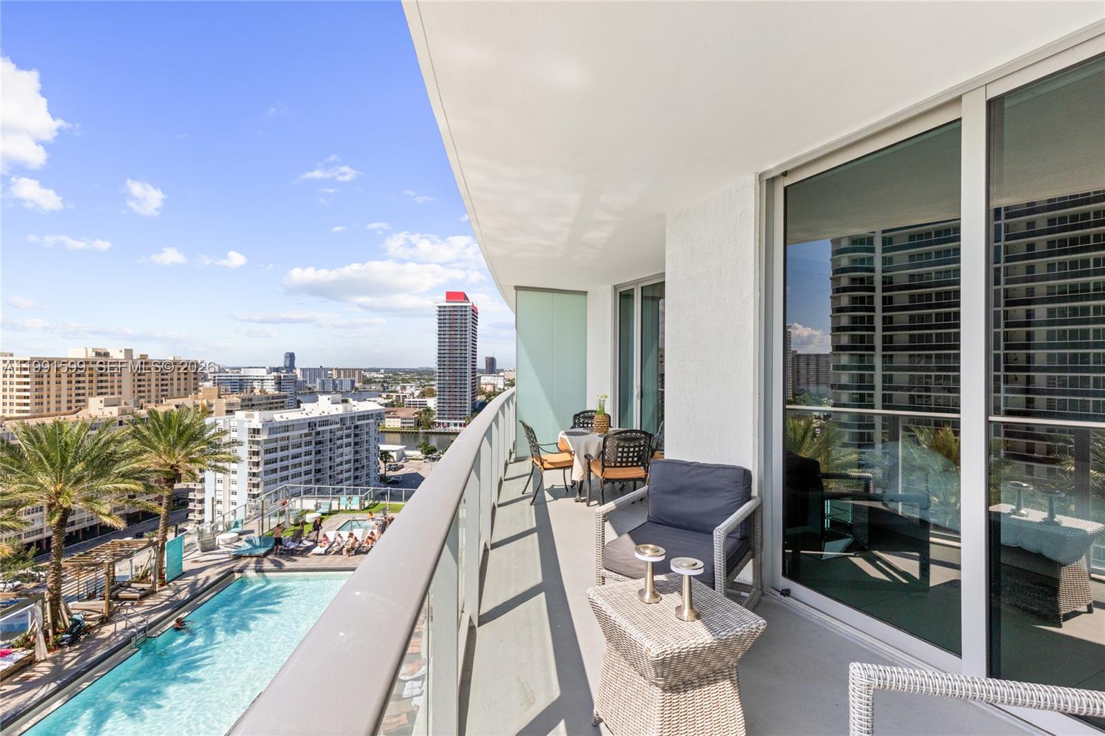 A high-rise balcony features outdoor furniture, a glass railing, and a view of a pool — 4111 S Ocean Dr # 1107, Hollywood FL 33019, HOLLYWOOD, FL