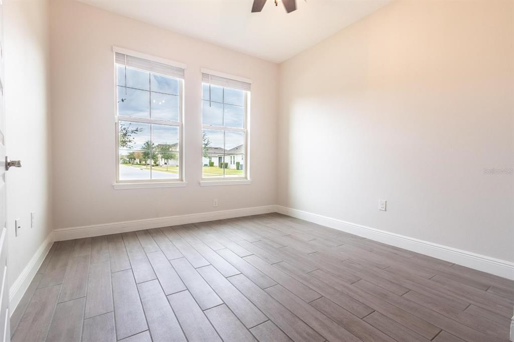 An empty room with light-colored walls, wood-look tile flooring, and two windows — 10207 ATWATER BAY DRIVE, WINTER GARDEN, FL