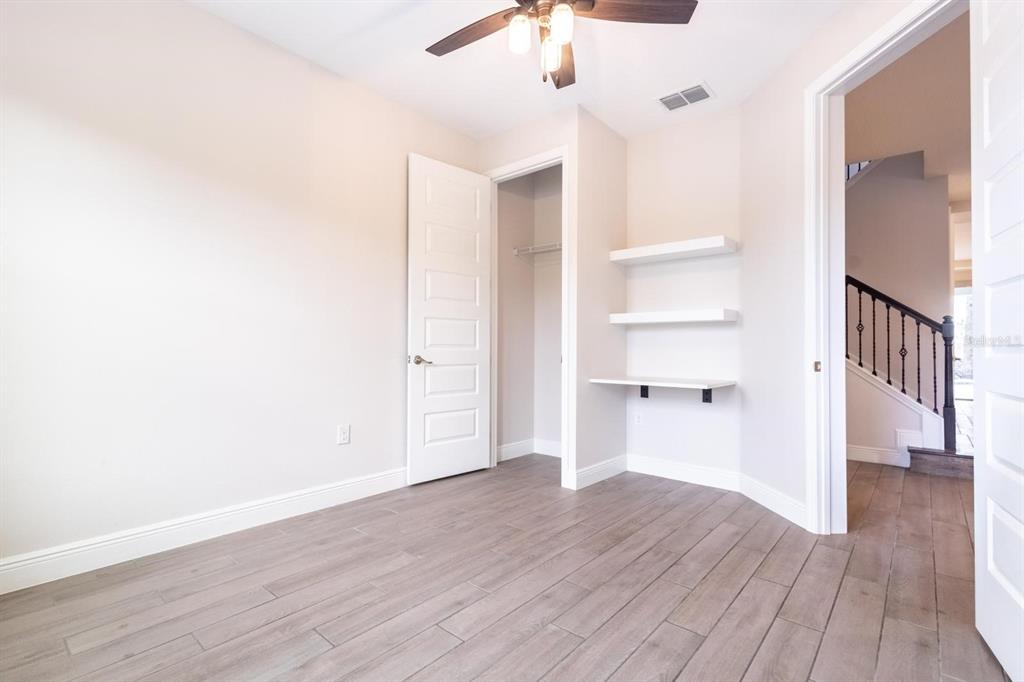 A room with light-colored walls, wood-look tile flooring, a closet, and built-in wall shelves — 10207 ATWATER BAY DRIVE, WINTER GARDEN, FL