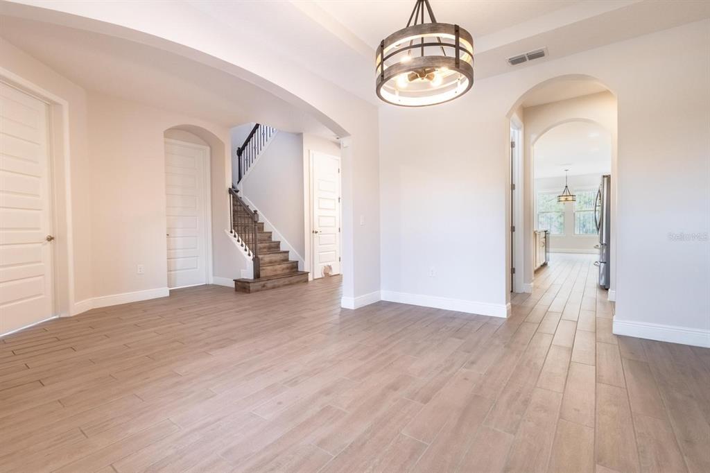 An interior view of a room with wood-look tile flooring, a staircase, and a chandelier — 10207 ATWATER BAY DRIVE, WINTER GARDEN, FL