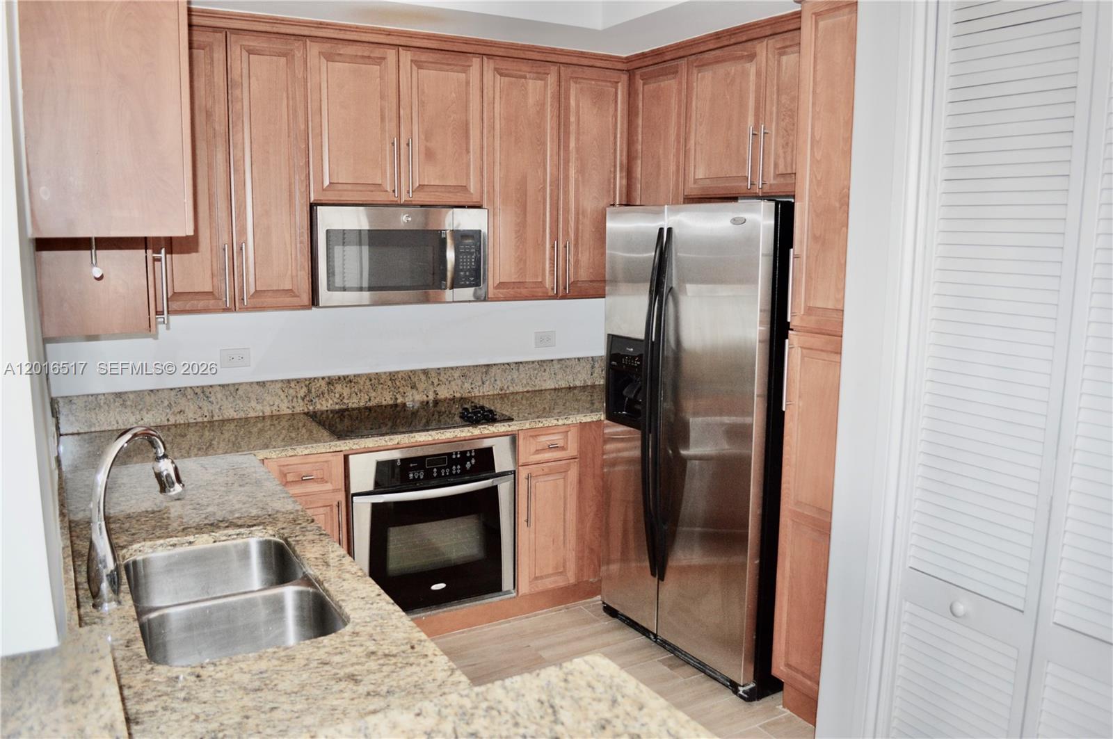 A kitchen features wood cabinets, granite countertops, stainless steel appliances, and a double sink — 1805 Ponce De Leon Blvd # 529, Coral Gables FL 33134, CORAL GABLES, FL