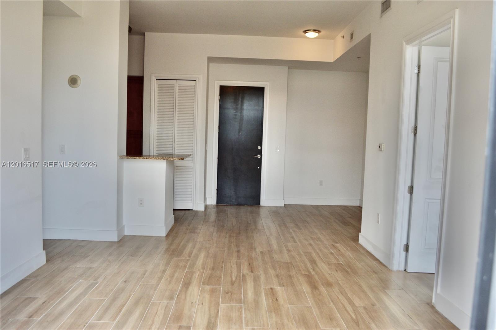 This interior view shows a room with light wood-look flooring, white walls, and a dark door — 1805 Ponce De Leon Blvd # 529, Coral Gables FL 33134, CORAL GABLES, FL
