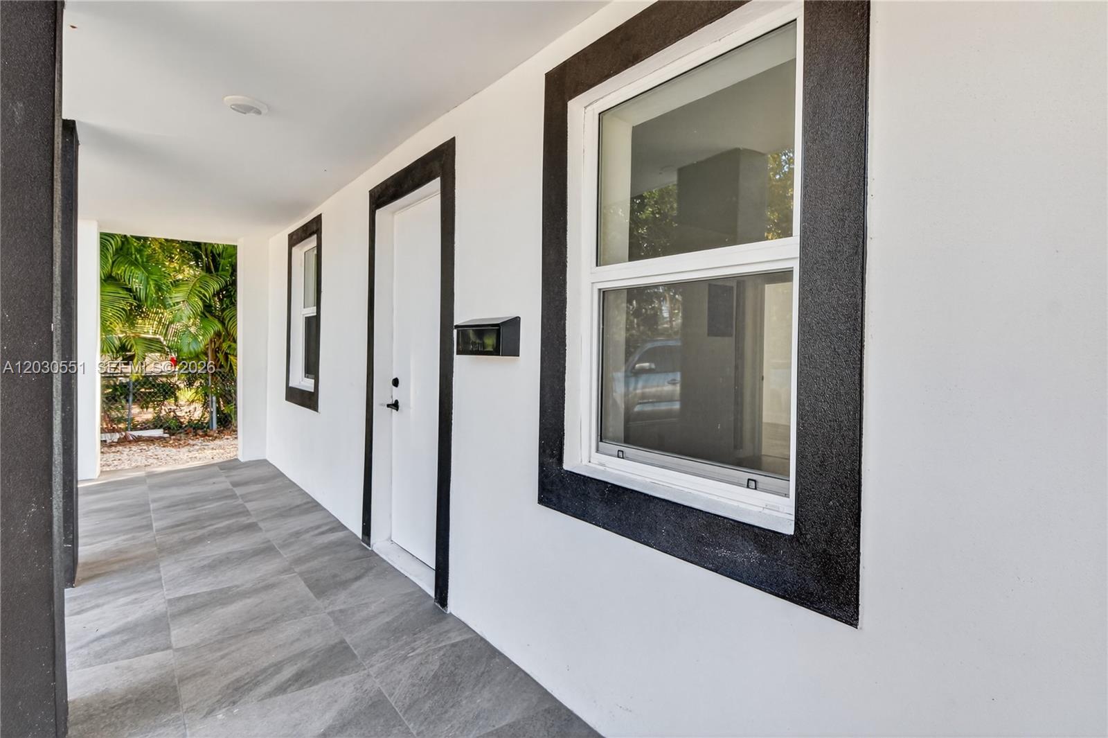 A white exterior wall features a door and window with black trim on a porch — 428 NW 97th St, Miami FL 33150, MIAMI, FL