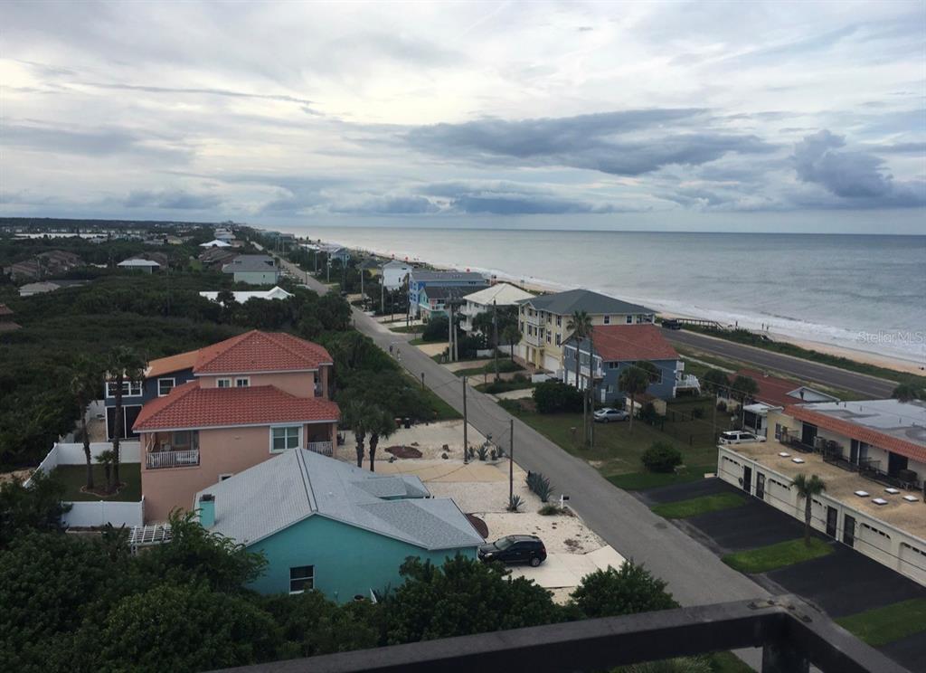 An aerial view shows a tall beachfront condominium building with a swimming pool and parking lot — 1601 CENTRAL AVENUE UNIT 704, FLAGLER BEACH, FL