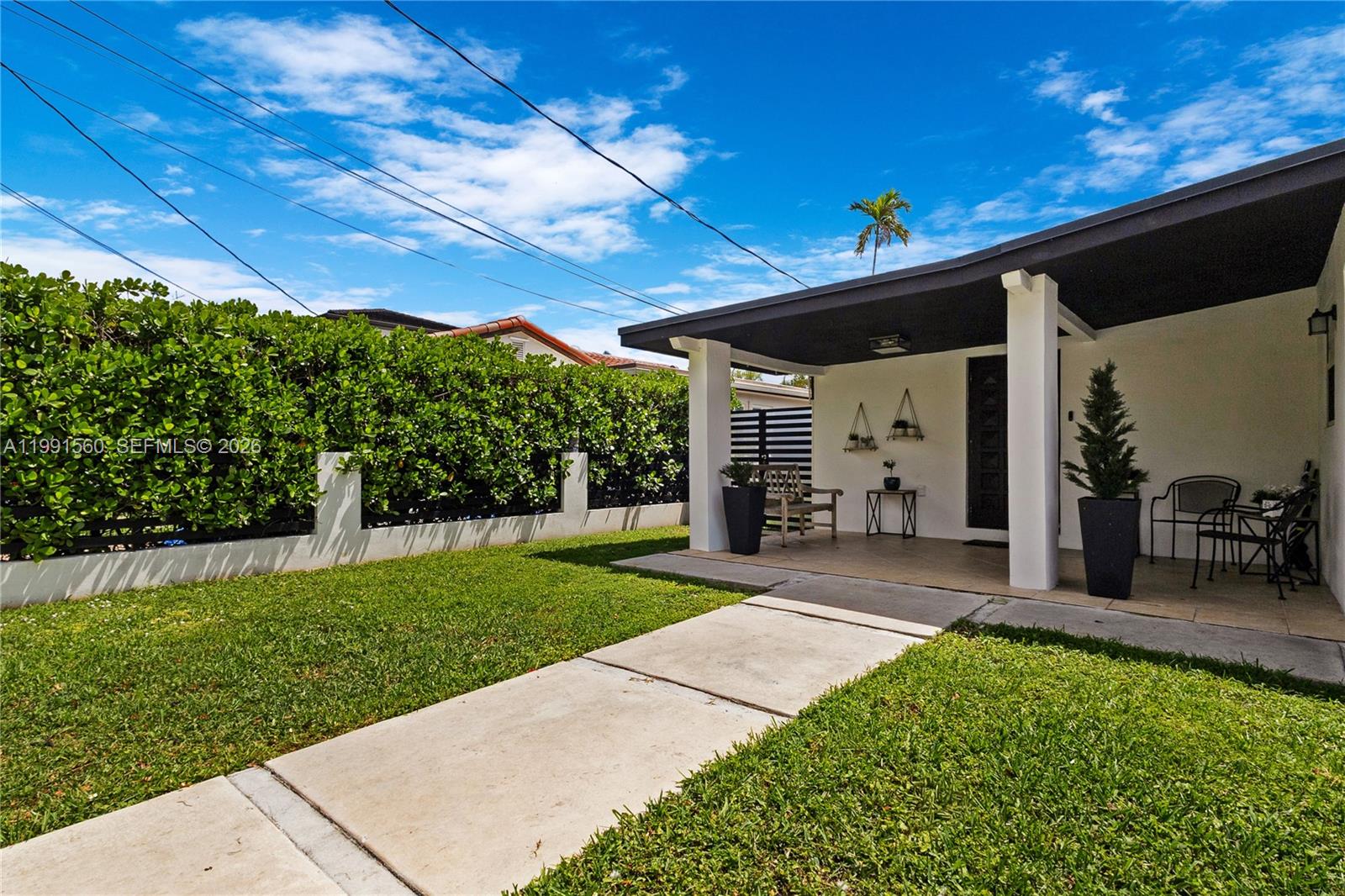 A single-story white house features a black-trimmed roof, a covered porch, and a black fence — 3500 SW 13th St, Miami FL 33145, MIAMI, FL