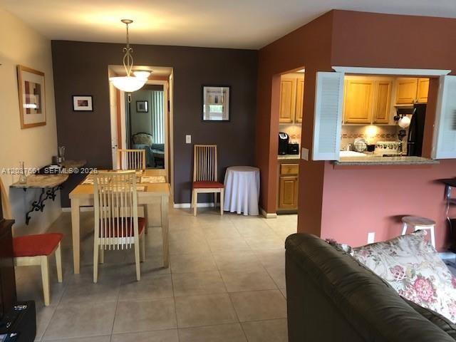 A dining area with a wooden table and chairs sits adjacent to an open kitchen — 366 Brighton I # 366, Boca Raton FL 33434, BOCA RATON, FL