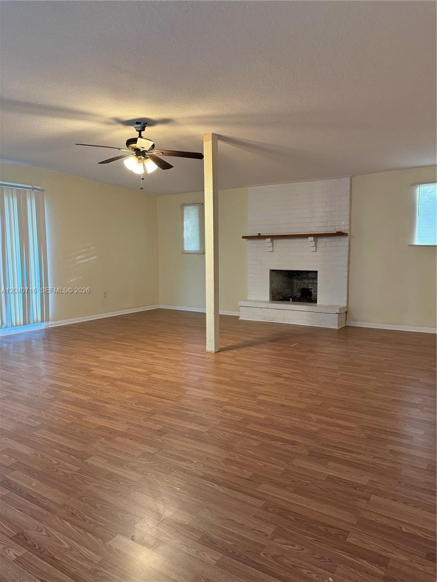 A living room features light-colored walls, wood-look flooring, a ceiling fan, and a brick fireplace — 9410 Gilchrist ct, Jacksonville FL 32219, JACKSONVILLE, FL