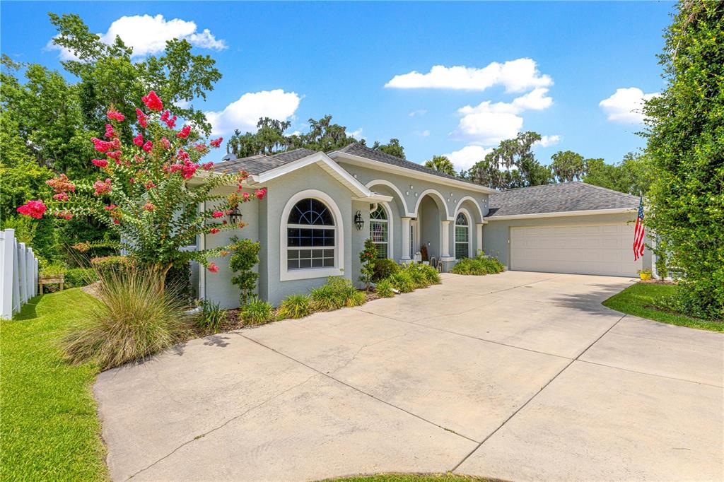 A single-story house with a gray exterior, arched windows, and a concrete driveway — 2616 SW 18TH AVENUE NE, OCALA, FL